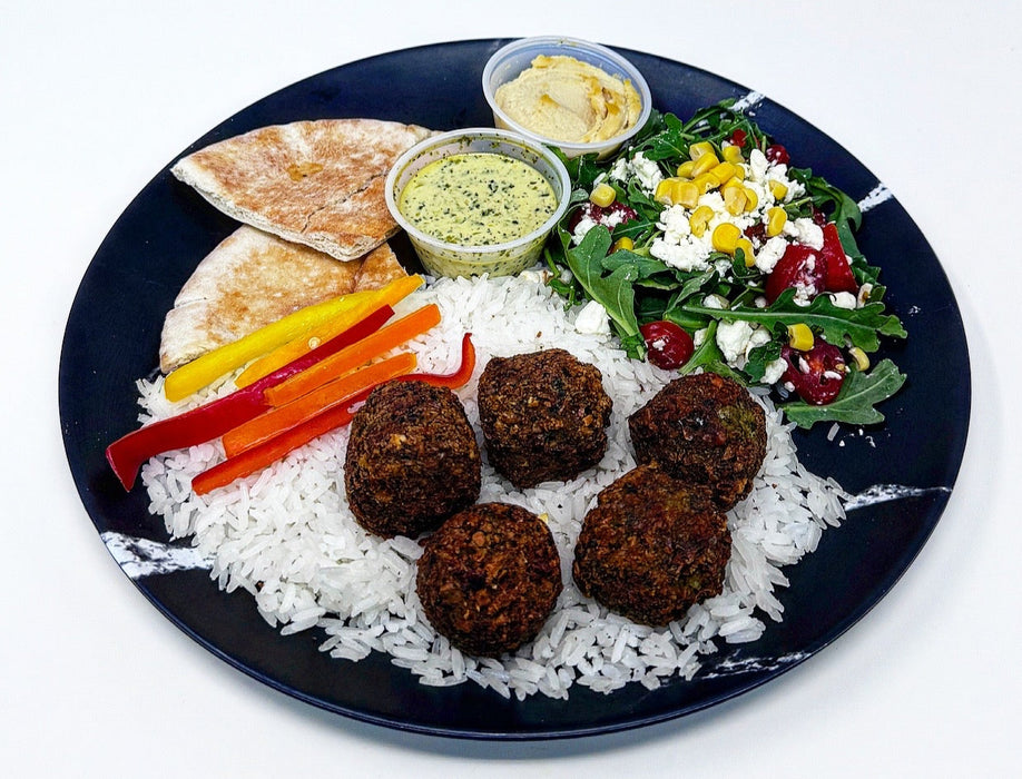Plated meal with falafel, rice, vegetables, and salad on a white background