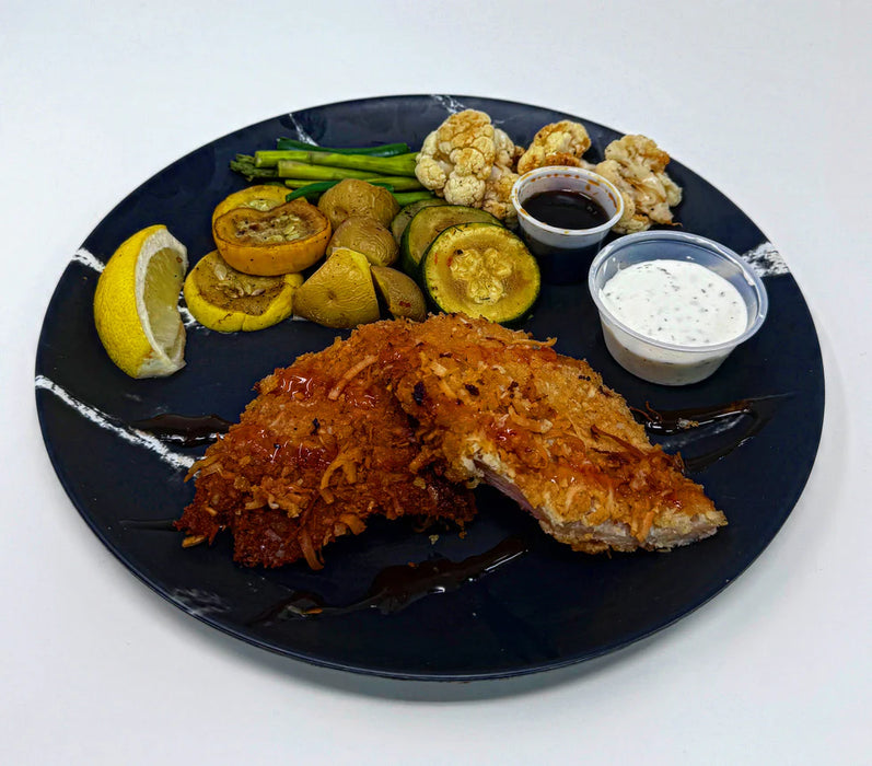 Plated dish with fried fish, vegetables, and sauces on a dark plate.