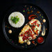 Plated dish with chicken breast, rice, and vegetables on a dark background