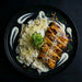 Plated dish with noodles, tofu, and sauce on a dark background