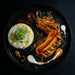 Plated dish with rice, vegetables, and meat on a dark background