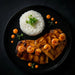 Plated dish with chicken breast, shrimp, and white rice on a black plate.