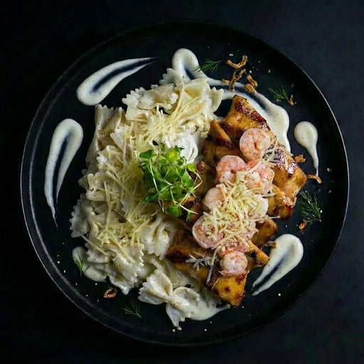 Plated dish with pasta, shrimp, and a creamy sauce on a dark background