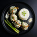 Plated dish with meatballs, rice, and asparagus on a black plate. The Halal Meal Prep
