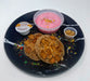 Two cookies with a pink dessert and small container on a black plate with white rim. The halal meal preps.