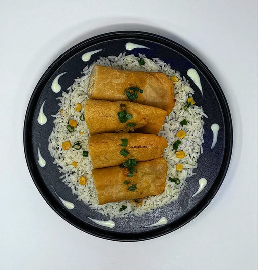 Platter with rice, spring rolls, and two small bowls of dipping sauces on a white background