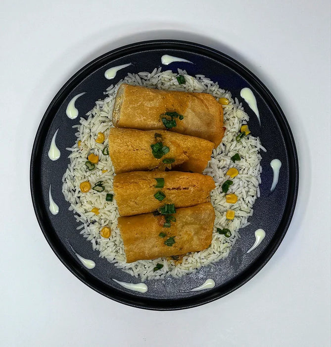 Platter with rice, spring rolls, and two small bowls of dipping sauces on a white background