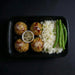 Plated meal with meatballs, rice, and green beans on a dark background