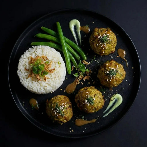 Plated dish with rice, green beans, and meatballs on a dark background. The Halal Meal Preps