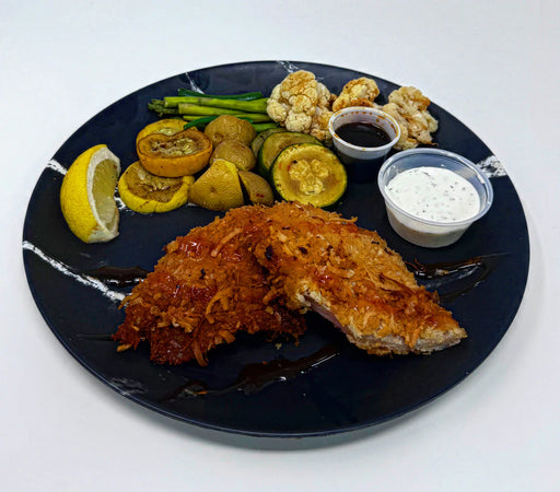 Plated dish with fried fish, vegetables, and sauces on a dark plate.
