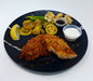 Plated dish with fried fish, vegetables, and sauces on a dark plate.