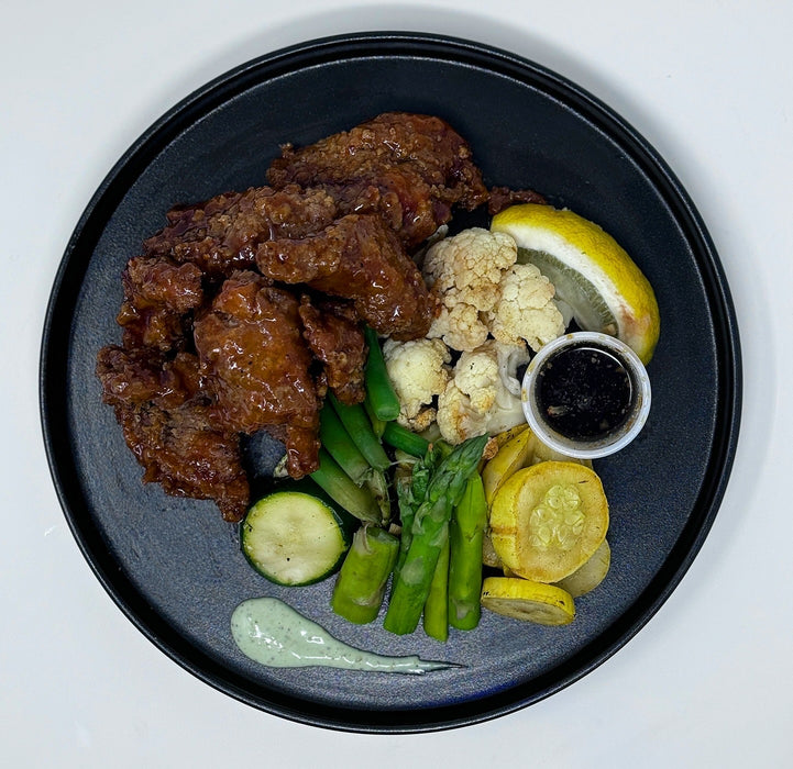 Plated dish with chicken wings, vegetables, and sauces on a dark plate. Made by The Halal Meal Preps, a NJ Meal Prep Delivery Company. 