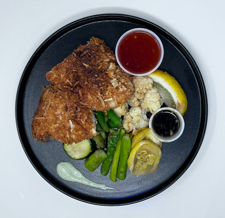 Plated dish with fried food, vegetables, and sauces on a black plate.