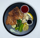 Plated dish with fried food, vegetables, and sauces on a black plate.