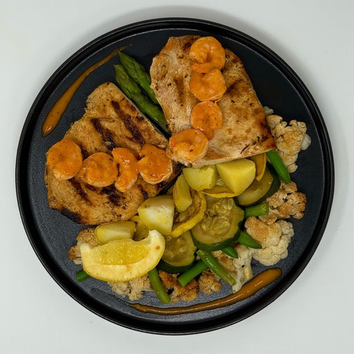 Plated dish with grilled bread, vegetables, and a lemon wedge on a white background