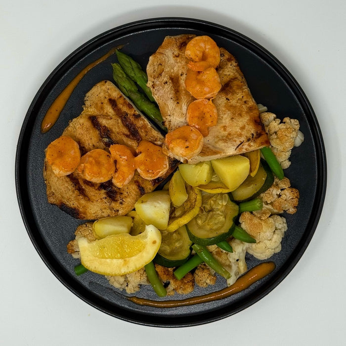 Plated dish with grilled bread, vegetables, and a lemon wedge on a white background