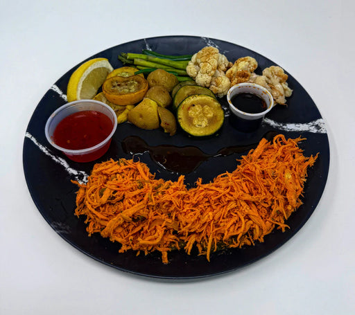 Assorted vegetables on a black plate with dipping sauces on a white background
