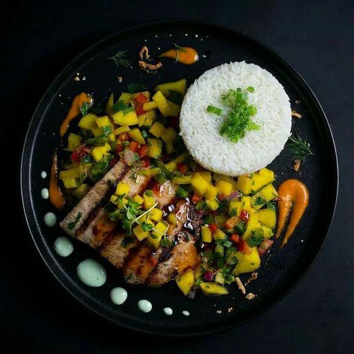 Plated dish with grilled meat, mango salsa, and white rice on a dark background. The Halal Meal Preps