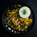 Plated dish with grilled meat, mango salsa, and white rice on a dark background. The Halal Meal Preps