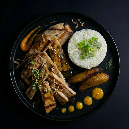 Plated dish with grilled fish, rice, and vegetables on a dark background