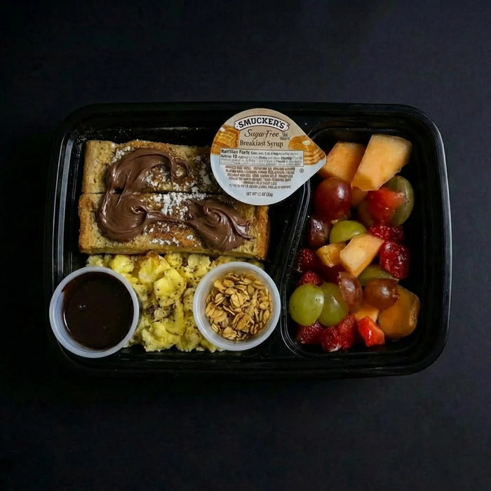 Breakfast tray with toast, eggs, fruit, and granola on a black background