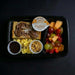 Breakfast tray with toast, eggs, fruit, and granola on a black background
