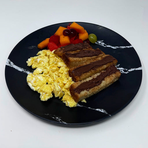 Breakfast plate with scrambled eggs, toast with chocolate spread, and fruit on a black marble-patterned plate.