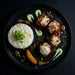 Plated dish with rice, meatballs, and sauces on a dark background. The Halal Meal Preps