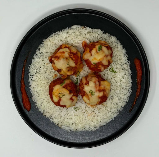 Plated dish with meatballs, vegetables, and a side of sauce on a white background