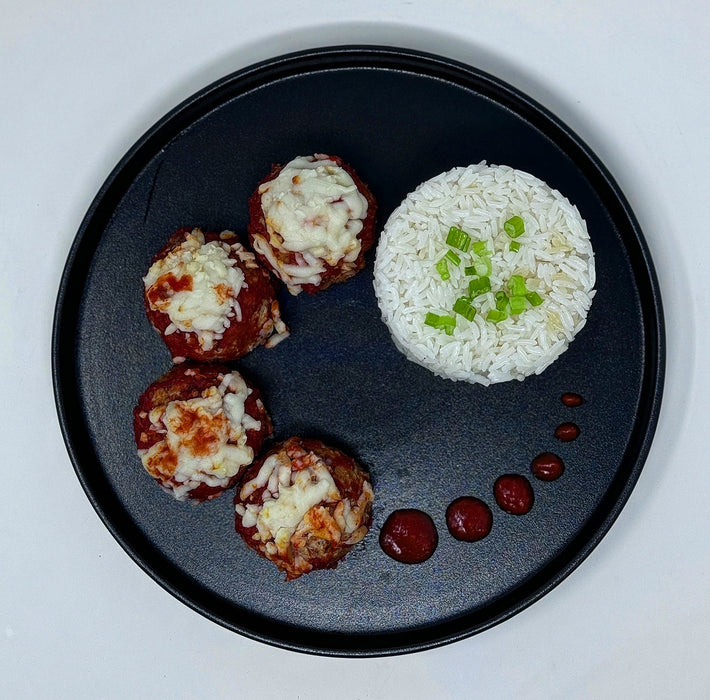 Black plate with meatballs and rice on a white background