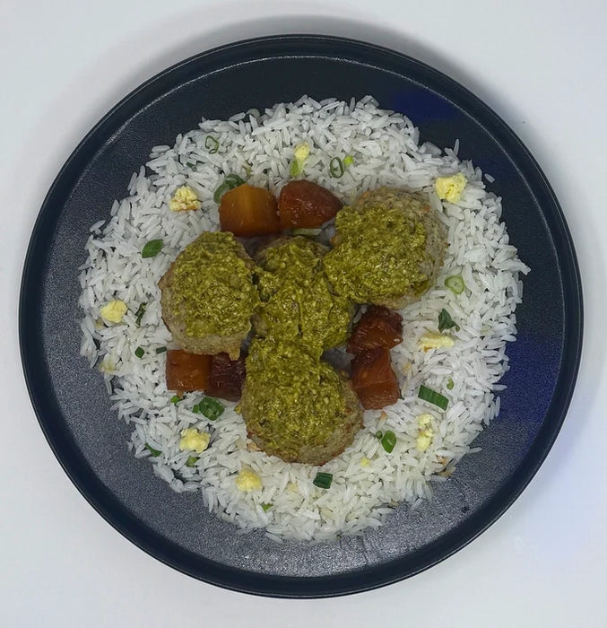 Ground chicken meatballs baked to perfection tossed in house pesto sauce paired with jasmine rice, green beans, and a side of fresh lemon and pineapples.