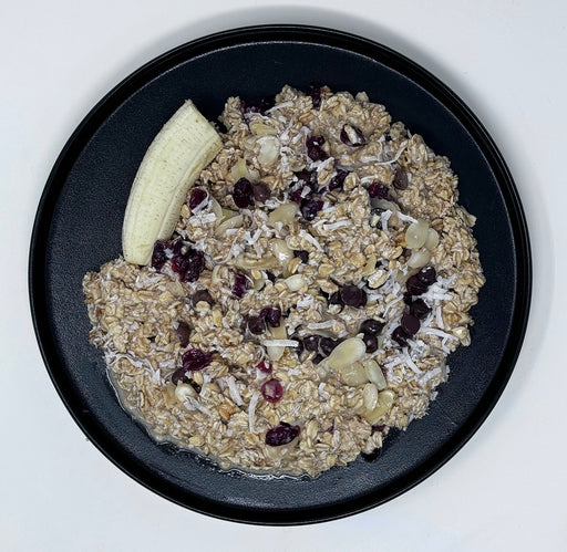 Oatmeal with dried fruits and a banana on a black plate
