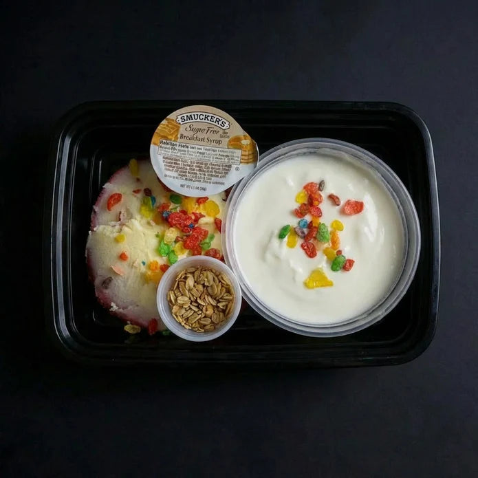 Yogurt with cereal and syrup on a black tray