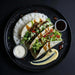 Tacos with rice and sides on a black plate. Meal made by the halal mela prep.