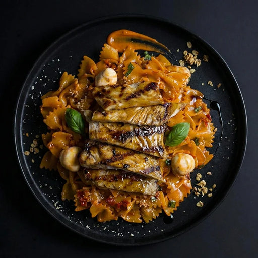 Plated dish of pasta with grilled eggplant and mushrooms on a dark background
