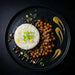 Plated dish with white rice, brown beans, and green onions on a dark background