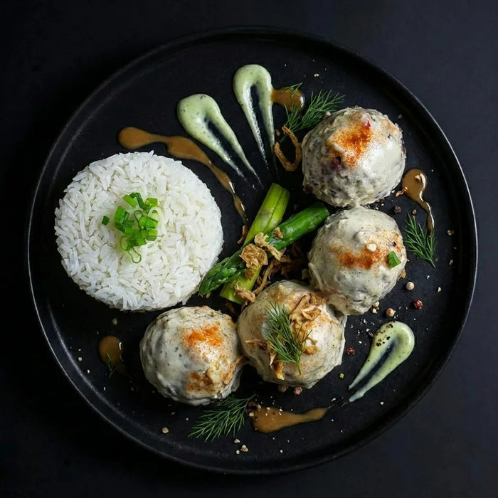 Plated dish with rice, meatballs, and vegetables on a dark background. The Halal Meal Preps