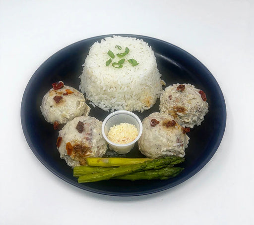 Dish with rice, meatballs, and asparagus on a white background