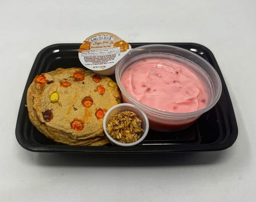 The Halal Meal Prep - Reeses PB Protein Pancakes -2 pancakes paired with a strawberry yogurt and granola on a black plate. 