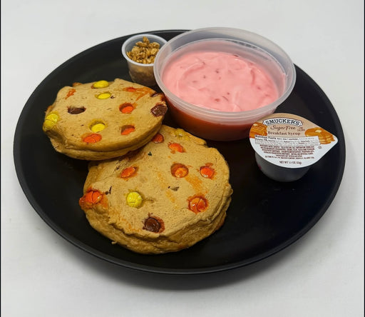 The Halal Meal Prep - Reeses PB Protein Pancakes -2 pancakes paired with a strawberry yogurt and granola on a black plate. 