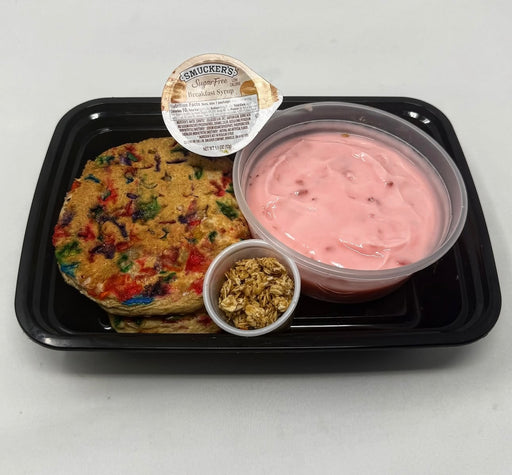 The Halal meal prep - Birthday Cake Protein Pancakes paired with yogurt granola and a sugar free syrup cup on a black plate