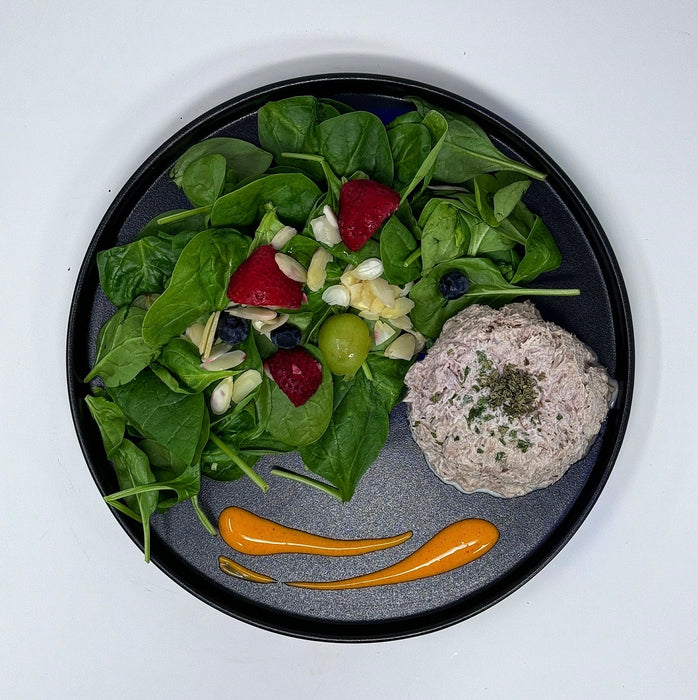 Platter with salad, fruit, and a patty on a white background