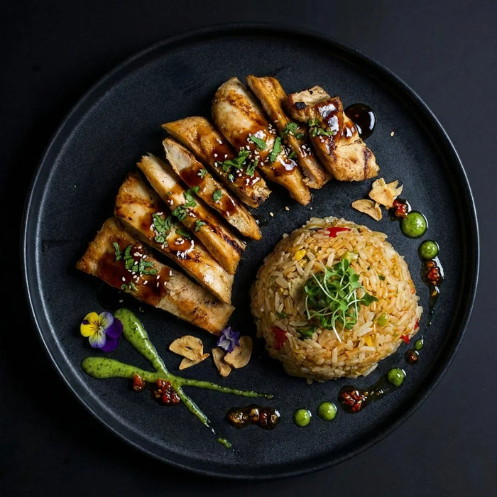 Plated dish with sliced chicken and fried rice on a dark background. The halal meal preps